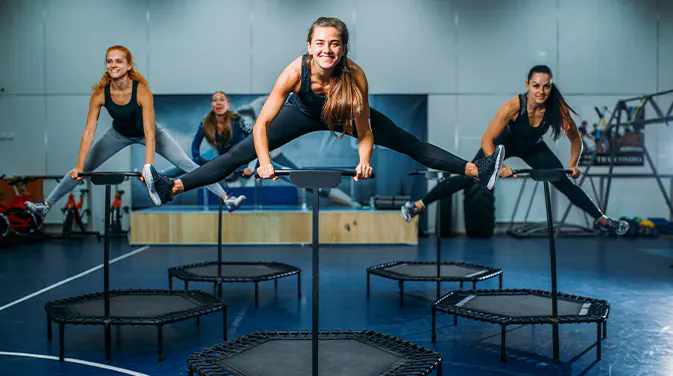3 Frauen im Fitnessstudio auf Trampolinen beim Jumping Fitness
