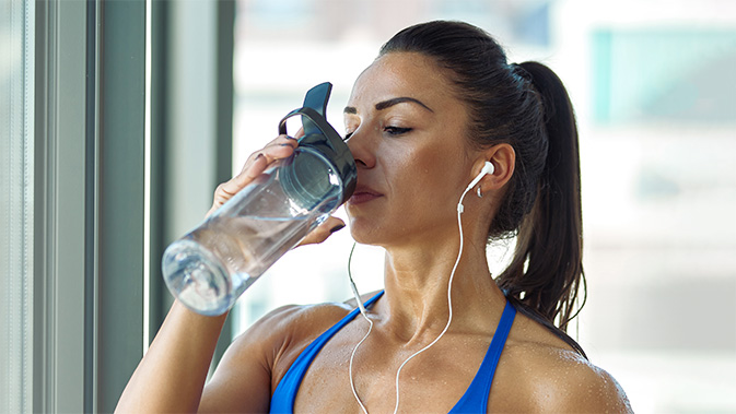 Eine verschwitzte Sportlerin trinkt Wasser