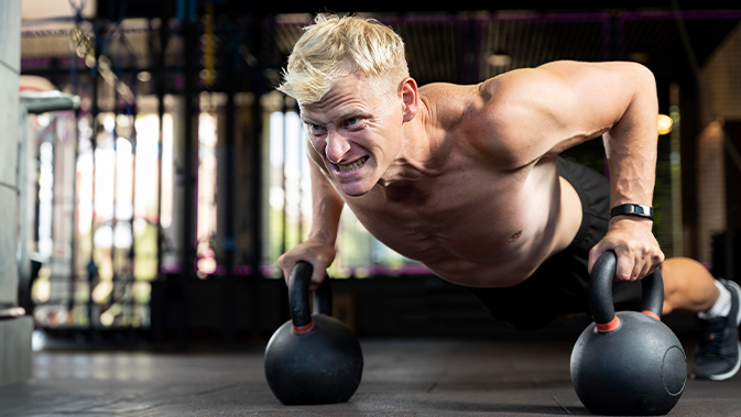 Ein Mann führt Push-Ups mit Kettlebells aus