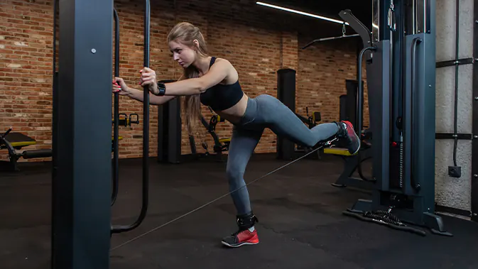 Gluteus Maximus Training mit Kickbacks am Kabelzug Frau im Gym macht Kickbacks am Kabelzug