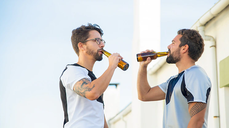 zwei Sportler trinken ein alkoholisches Getränk
