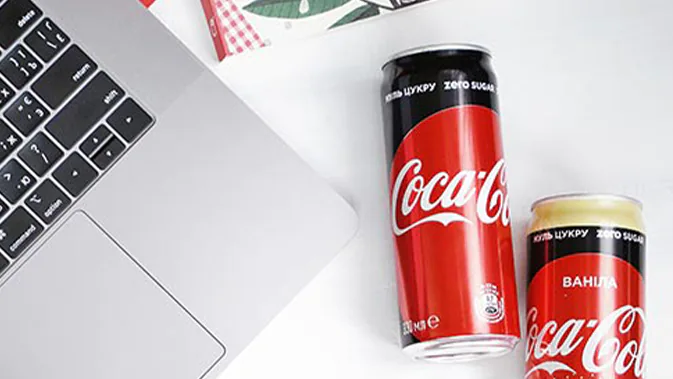 Zwei Coke Zero Dosen neben einem Laptop auf dem Schreibtisch