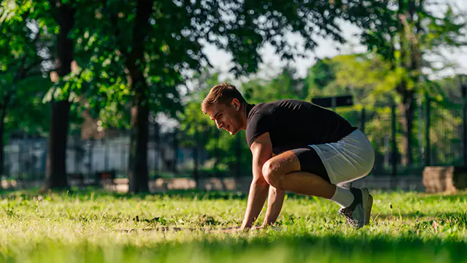 Mann auf einer Wiese in der Position nach einem Handstand