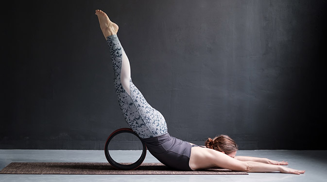 Die Übung Shalabhasana kann wunderbar mit dem Yoga-Rad abgewandelt werden. Bei der Übung wird besonders die untere Rücken- und die Gesäßmuskulatur beansprucht.