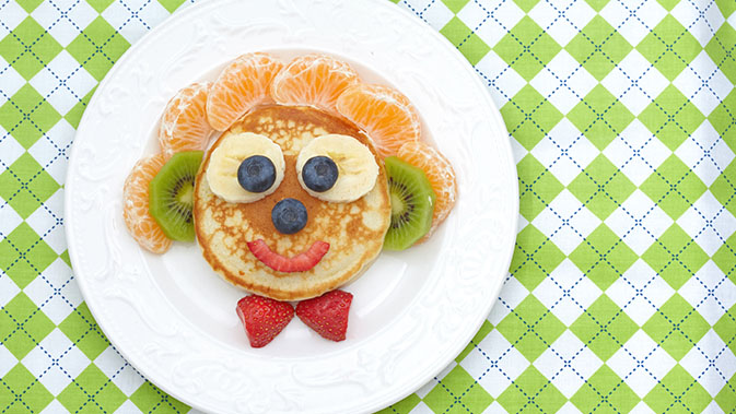 Ein bunter Teller für Kinder, bestehend aus Pfannkuchen und jede Menge Früchten.