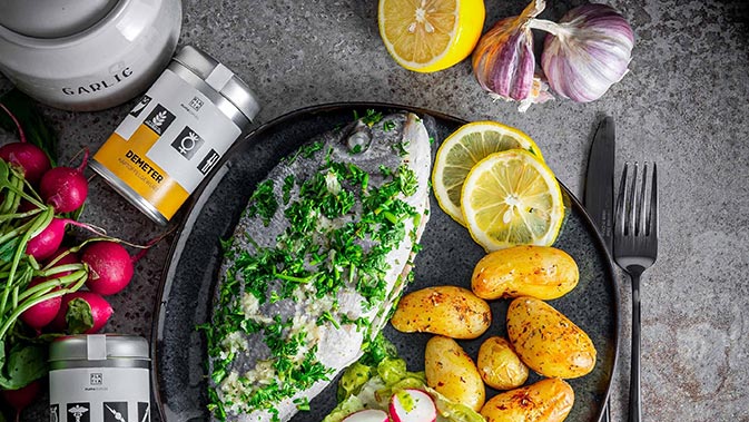 Mahlzeit bestehend aus gegrilltem Fisch, Kartoffeln und Salat.