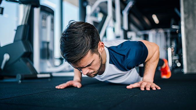 Mann macht Push-Ups im Fitnessstudio