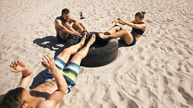 3 Personen machen Sport im Sand
