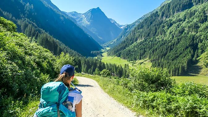 Frau mit Rucksack auf einem Wanderweg in den Bergen