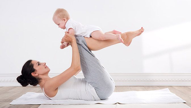 Frau macht Sportübung auf dem Boden mit Baby