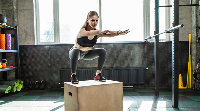 Frau steht auf einer Plyo-Box