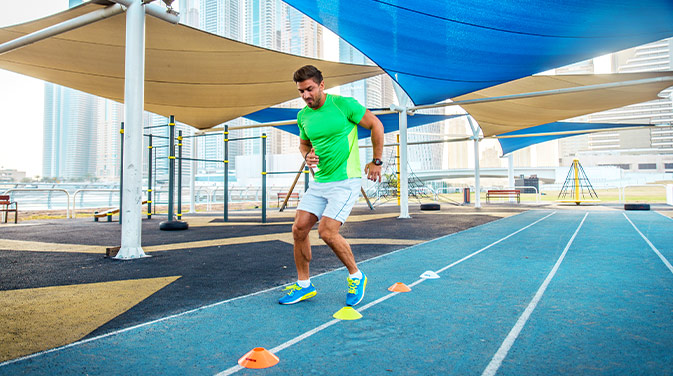 sportlicher Mann trainiert auf einer türkisfarbenen Tartanbahn