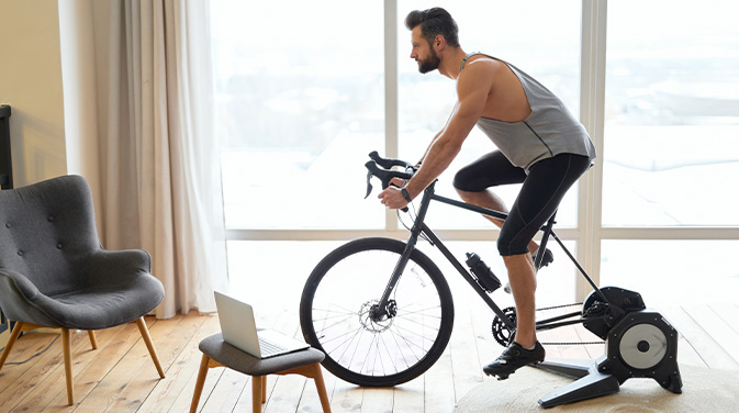 Mann auf einem Indoor-Cycling-Rad in einer Wohnung