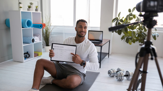 Trainer im Wohnzimmer, der Trainingsvideos aufnimmt