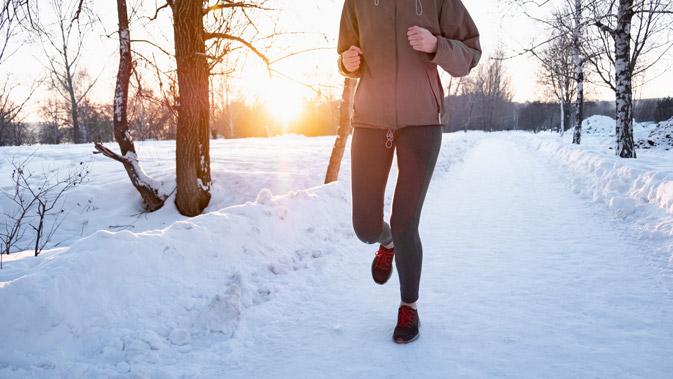 Person joggt auf einem schneebedeckten Weg in der Sonne