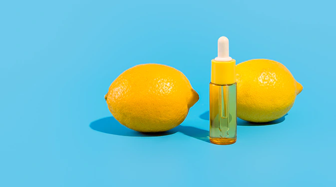 zwei Zitronen neben einer flasche flüssigem Vitamin C