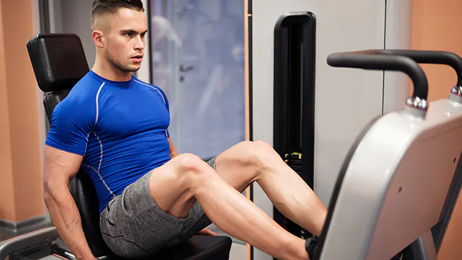 Im Gym können Fußballer ihre Kraft trainieren. Ein sportlicher Mann auf der Beinpresse