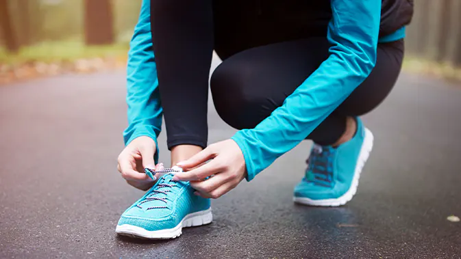 Person bindet sich die Laufschuhe