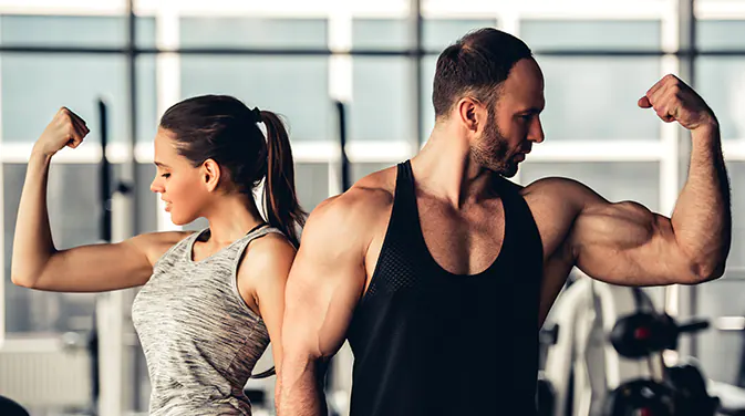 Frau und Mann im Fitnessstudio spannen ihren Bizeps an