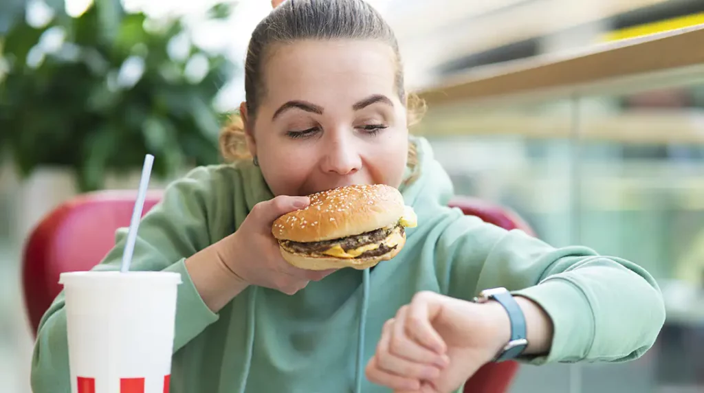 Eine Frau isst gestresst eine üppige Mahlzeit zwischendurch