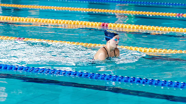 Eine Frau mit Schwimmbrille schwimmt im Schwimmbecken Bahnen