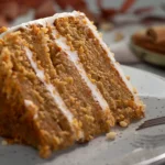 Ein Stück Carrot Cake mit mehreren Schichten aus Teig und einem Frischkäse Frosting