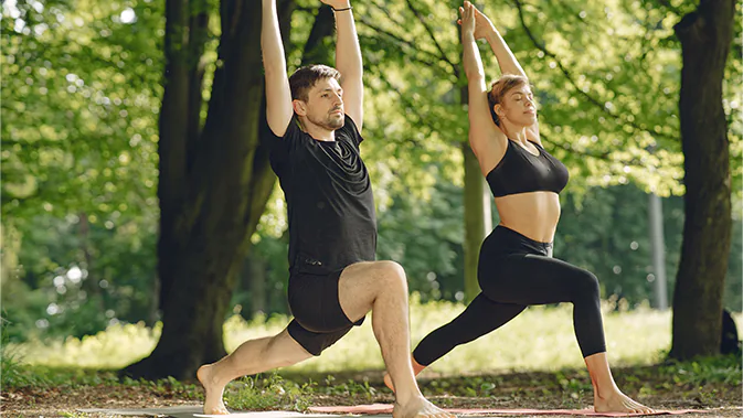 Zwei Personen, die gerade Yoga in einem Park praktizieren. 
