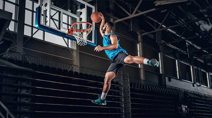 Ein Basketballer in der Pose während eines Slam-Dunks