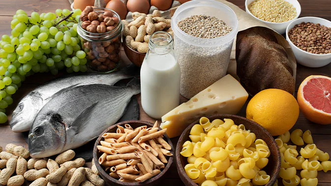 Verschiedene Lebensmittel mit proteinhaltigen Lebensmitteln auf einem Tisch, z. B. frischer Fisch, Käse, Milch, Nüsse.