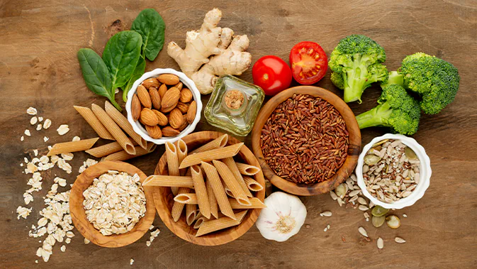 Eine Vielfalt an frischen Lebensmitteln ist nebeneinander ausgebreitet. Nudeln, Blumenkohl, Tomaten, Samen, Ingwer und weitere.