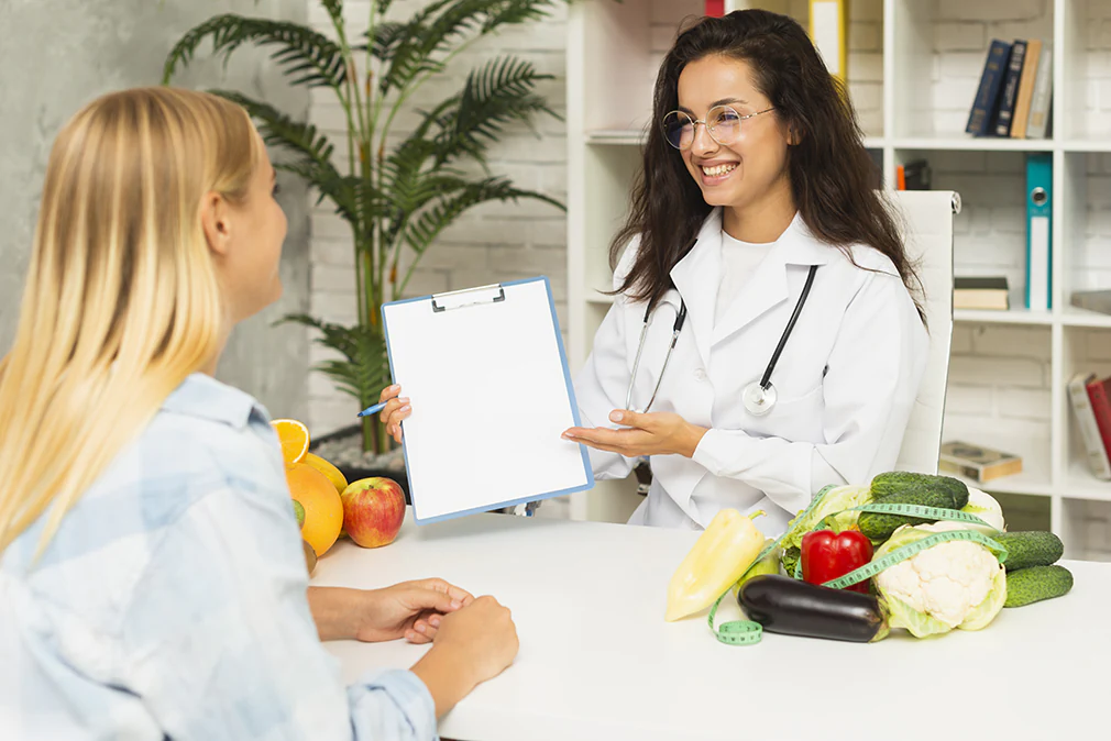 Ernährungsberaterin berät Patientin mit frischem Obst und Gemüse zur gesunden Ernährung.