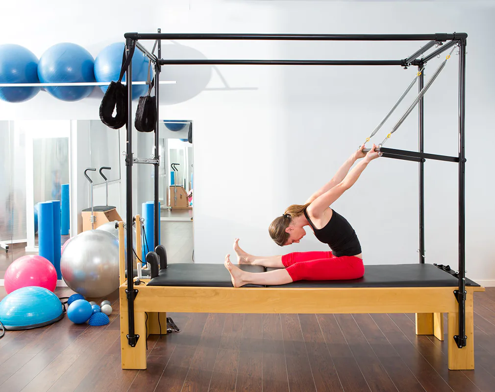 Frau macht Pilates Reformer-Übungen auf dem Cadillac-Gerät im Studio.