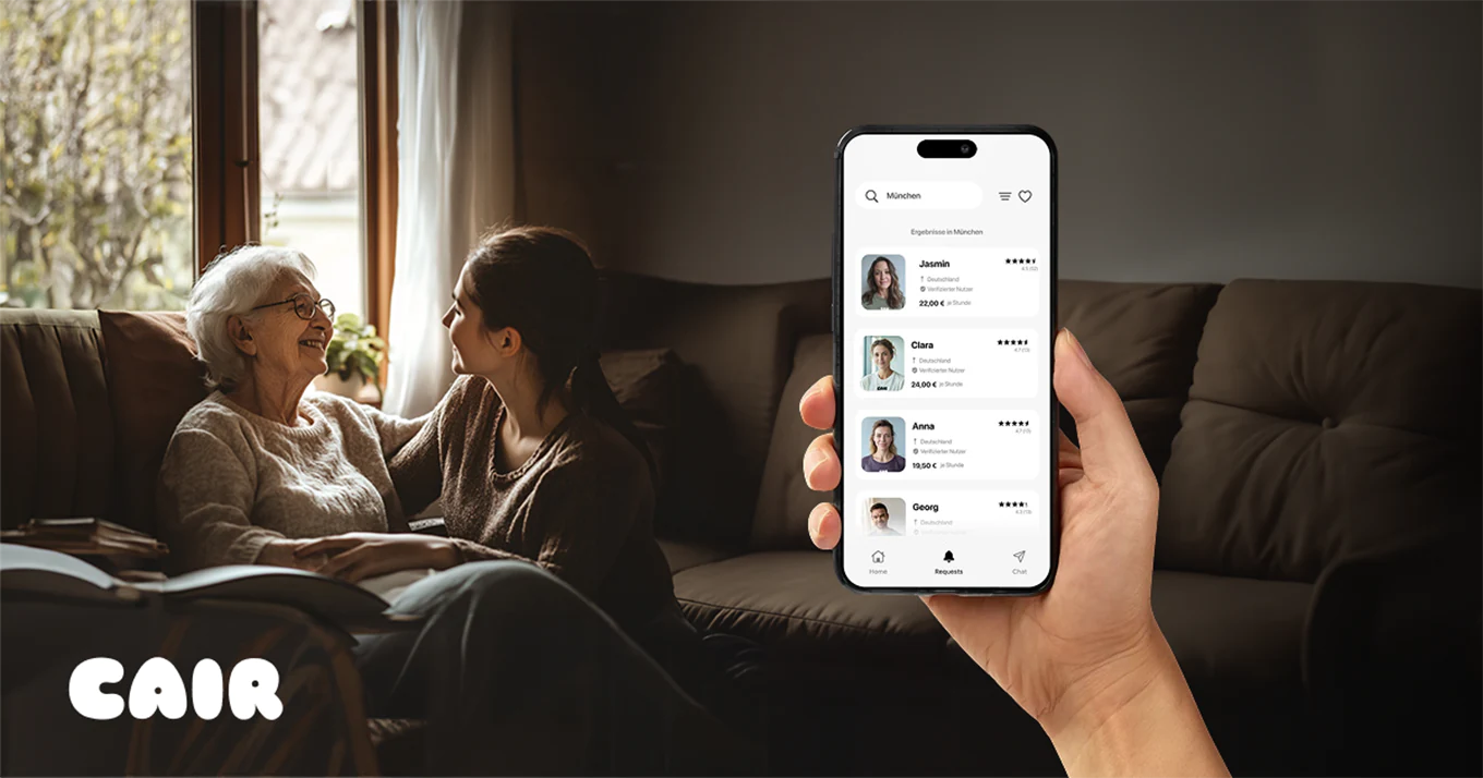 Ältere Frau mit junger Frau auf dem Sofa, im Vordergrund Smartphone mit Betreuungs-App CAIR