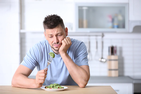 Mann schaut traurig auf sein Essen